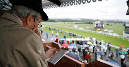 man at horse racing track with betting slip